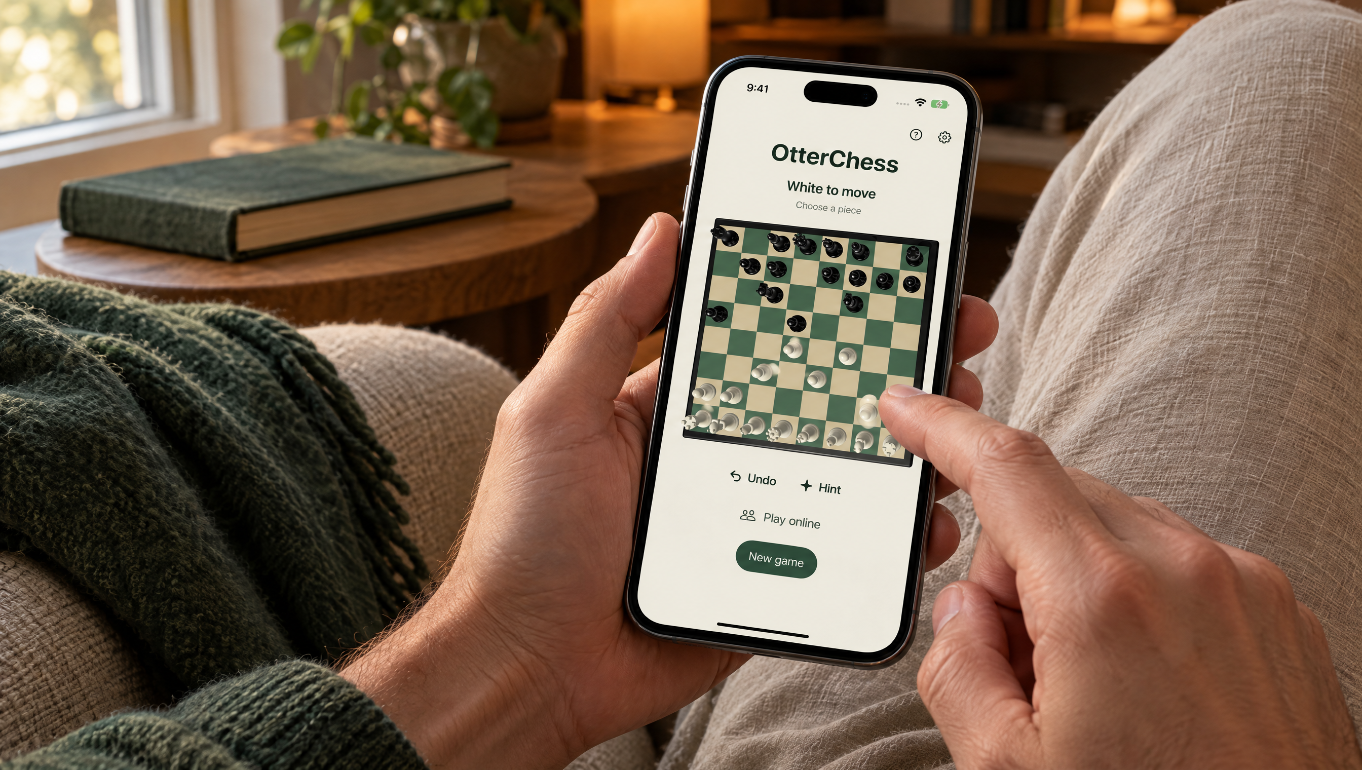 Hands playing OtterChess on an iPhone in a cozy armchair